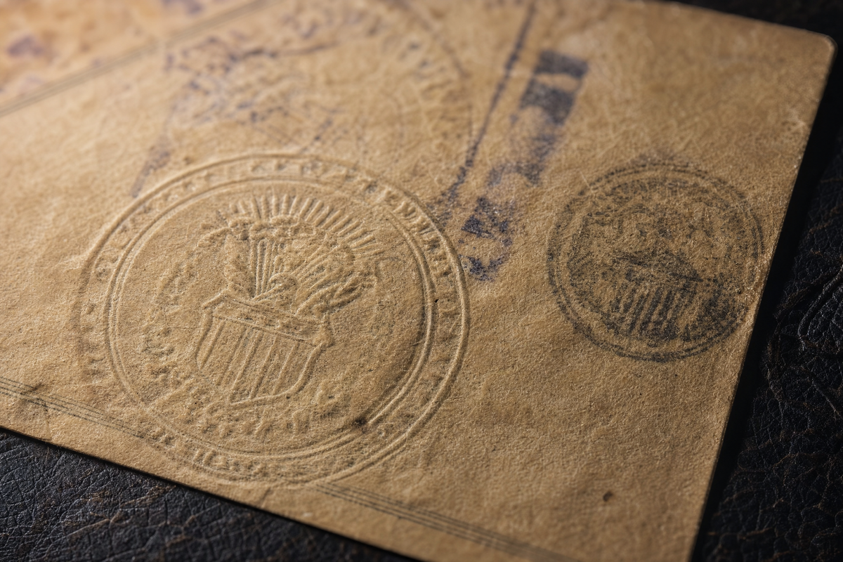 a close-up of an old federal tax stamp document with a faded stamp and official seals